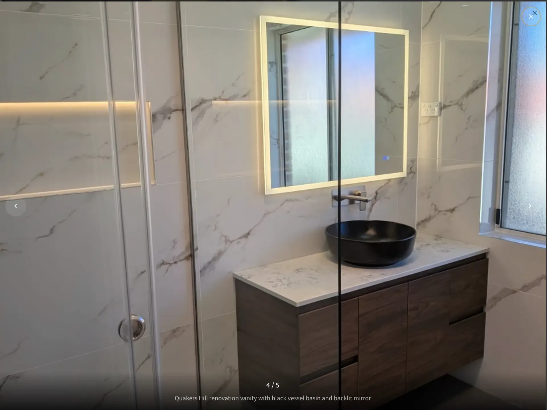 Quakers Hill luxury bathroom renovation with marble-look tiling, black vessel basin and backlit mirror
